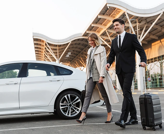Business couple arriving in style with luggage and luxury car