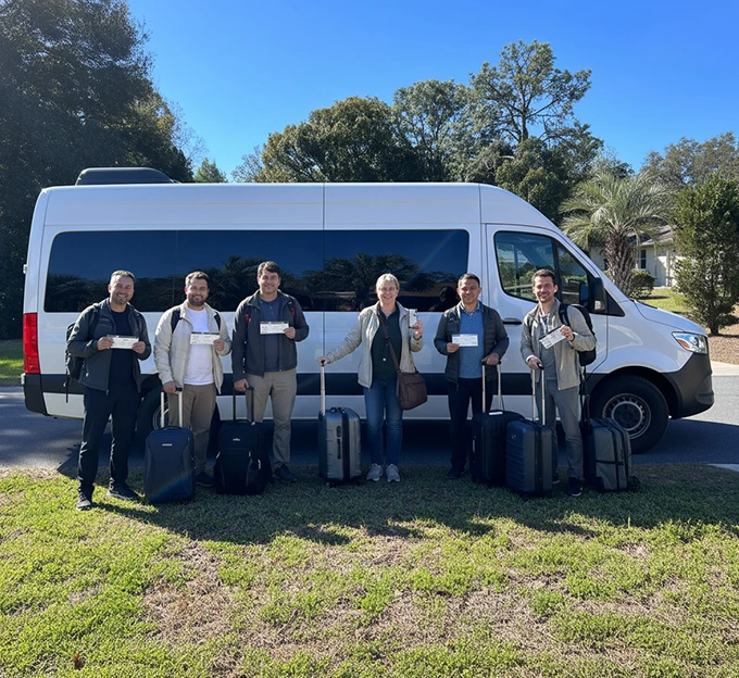 Group with luggage ready for business transportation near a white van.