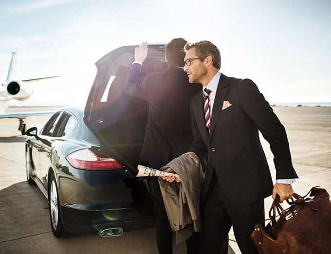 Businessman exiting car with luggage near private jet. Upscale transportation.